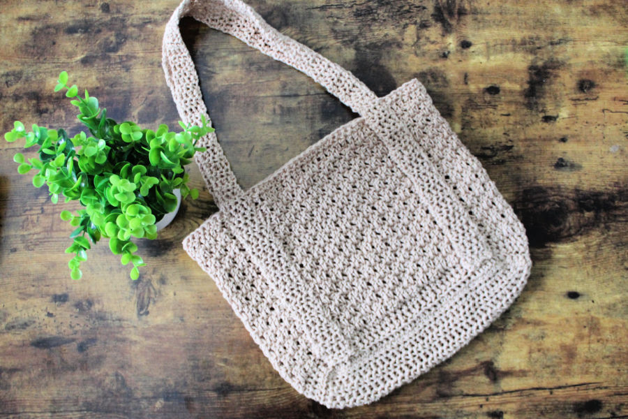 Crocheted bag, plant, wood surface